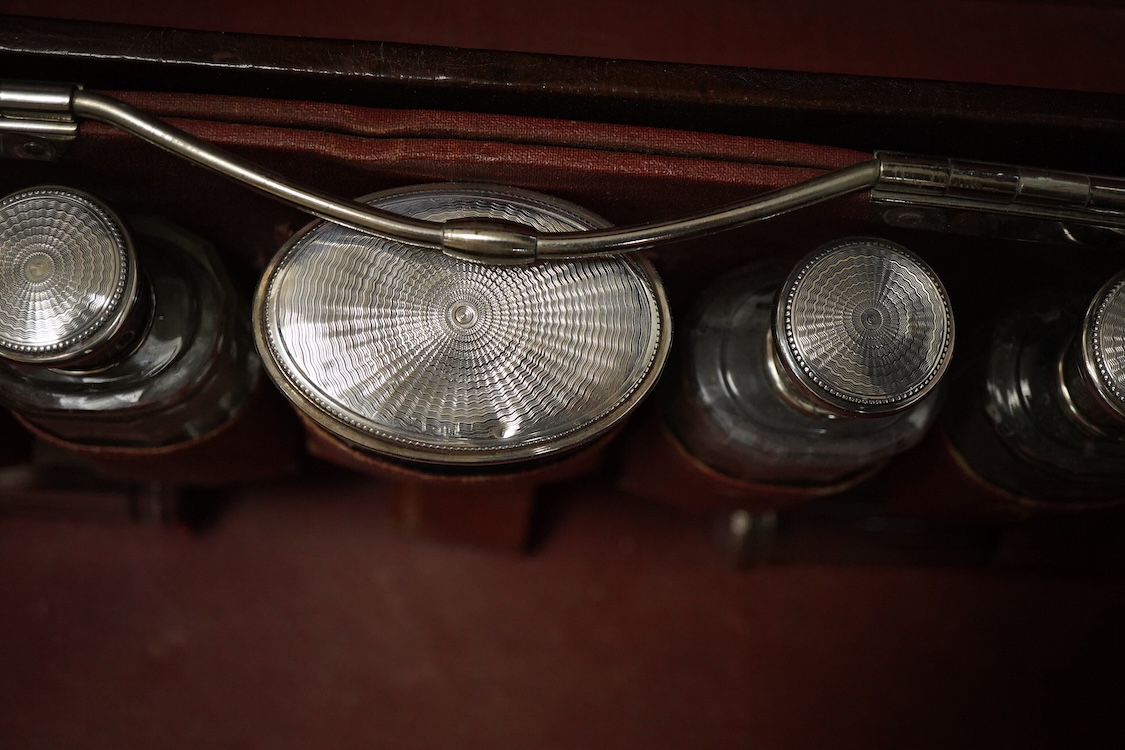 An early 20th century leather travelling toilet case, with 'Peninsular & Oriental Steam Navigation Compy' paper labels, containing eight French 950 standard white metal mounted glass toilet jars and one English silver mo